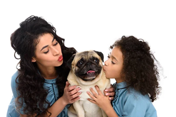 Mother and daughter kissing cute pug isolated on white — Stock Photo