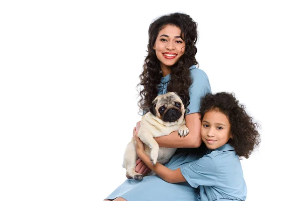 Madre e hija abrazando adorable pug aislado en blanco - foto de stock