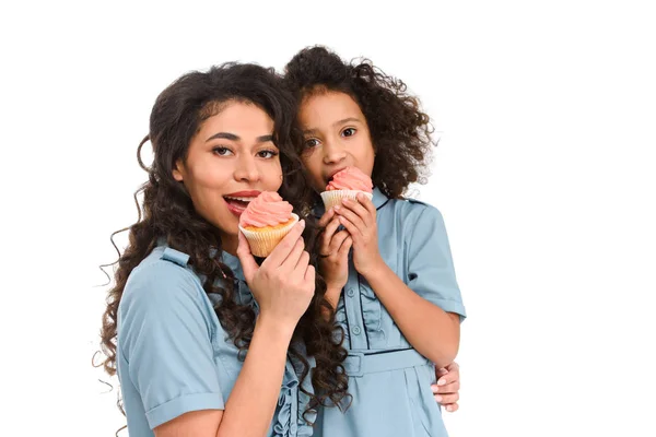 Mère et fille manger de délicieux cupcakes avec crème isolée sur blanc — Photo de stock