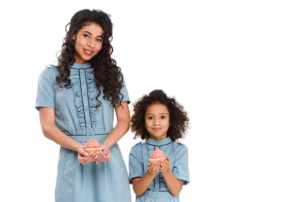 Красивая мать и дочь с вкусными кексами изолированы на белом — стоковое фото