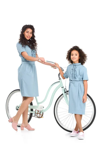 Madre e hija de pie con bicicleta aislada en blanco - foto de stock