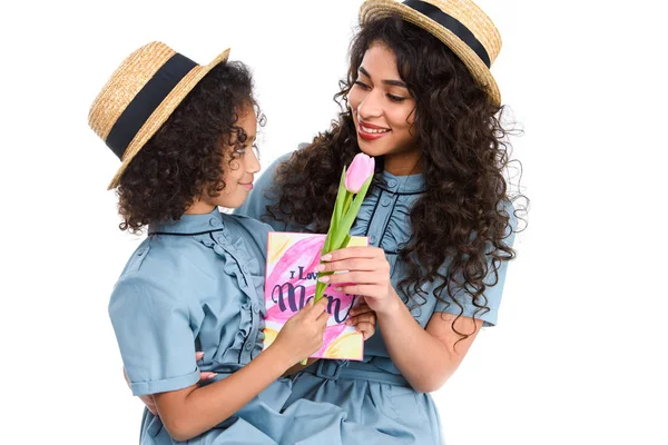 Madre e hija con tarjeta de felicitación del día de las madres y flor aislada en blanco - foto de stock