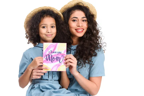 Happy mother and daughter with mothers day greeting card looking at camera isolated on white — Stock Photo