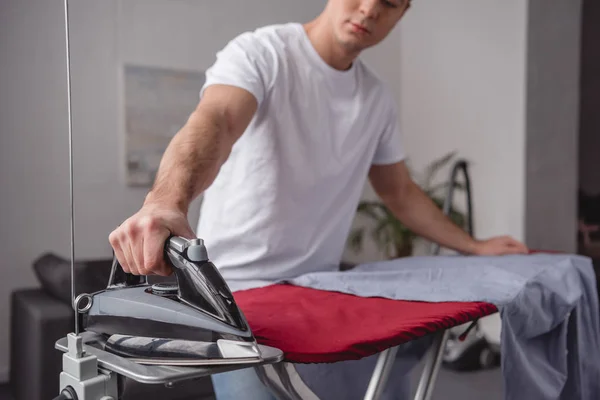 Imagen recortada del hombre tomando hierro para planchar camisa - foto de stock