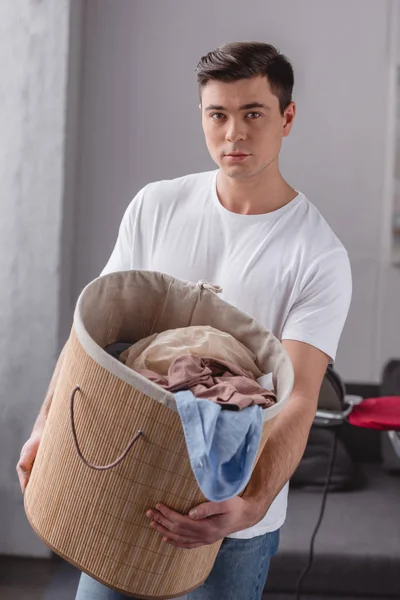 Schöner Mann mit Wäschekorb und Blick in die Kamera — Stockfoto