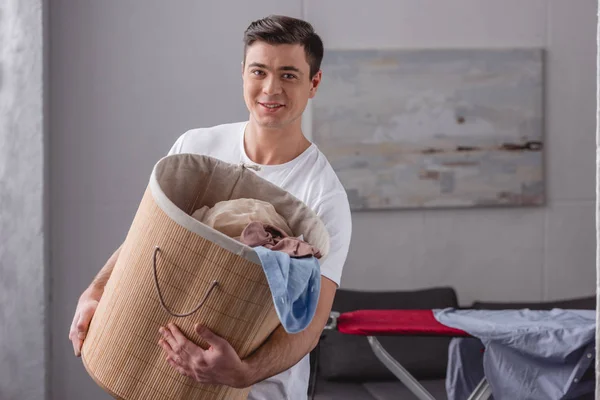 Smiling man holding basket with laundry — Stock Photo