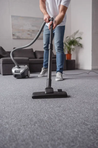 Imagem cortada de homem aspirando tapete na sala de estar — Fotografia de Stock