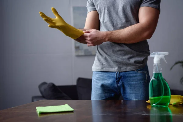 Imagem cortada do homem usando luvas de borracha para limpar a sala de estar — Fotografia de Stock