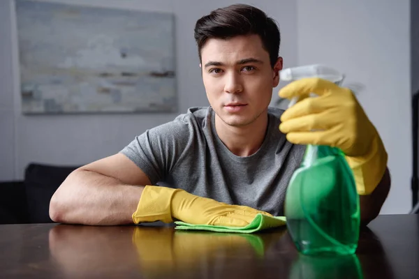 Guapo hombre sosteniendo spray botella y trapo - foto de stock