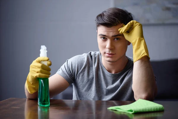 Bel homme avec vaporisateur et gants en caoutchouc regardant la caméra — Photo de stock