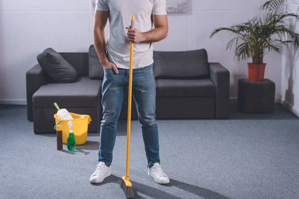 Imagem cortada do homem de pé com vassoura na sala de estar — Fotografia de Stock