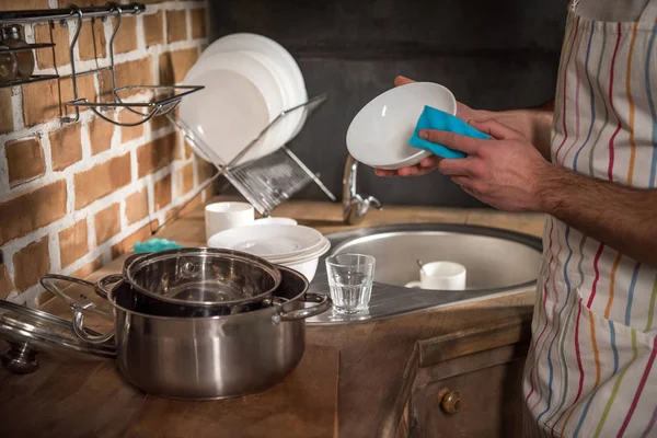 Обрезанный образ человека, моющего посуду на кухне — стоковое фото