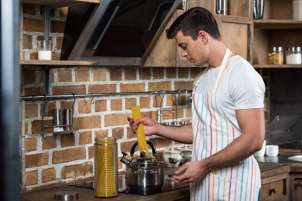 Vue latérale du bel homme cuisson des pâtes à la cuisine — Photo de stock