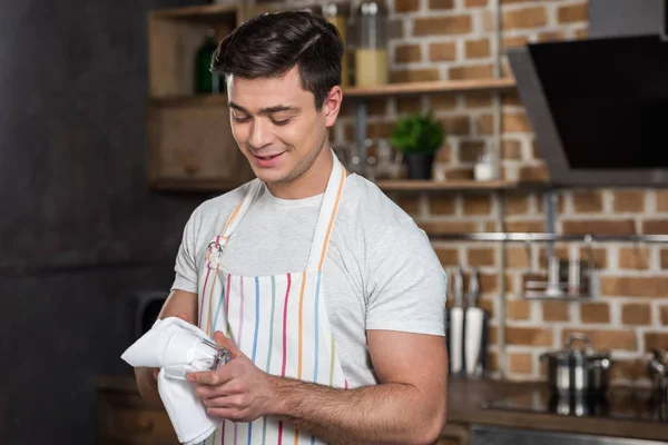 Homem bonito limpando vidro com toalha limpa na cozinha — Fotografia de Stock