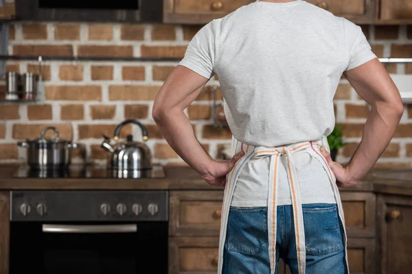 Imagem cortada de homem de pé em avental na cozinha — Fotografia de Stock