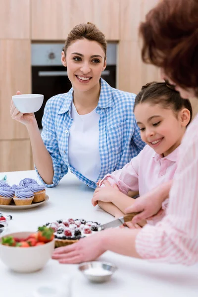 Tre generazioni di donne felici che trascorrono del tempo insieme in cucina e mangiano dolci in cucina — Foto stock