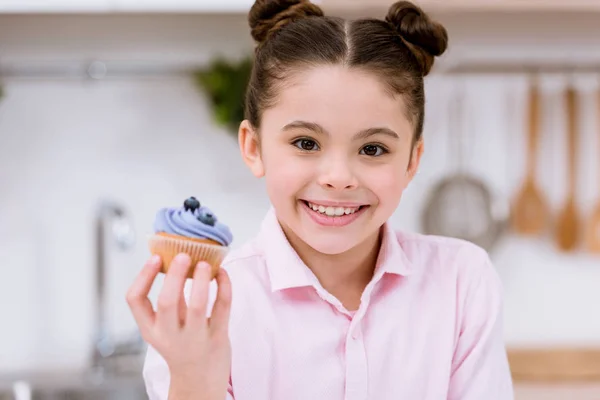 Close-up portrait of little child holding blueberry cupcake — Stock Photo