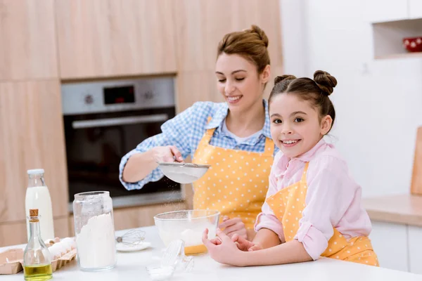 Happy mother and daughter with sieve preparing dough for pastry together — Stock Photo