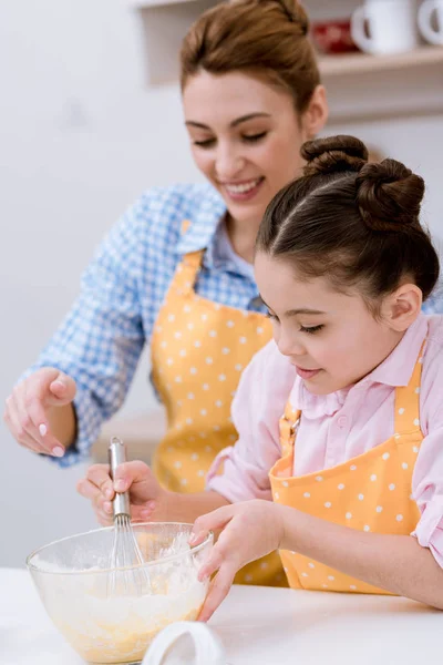 Счастливая мать и дочь смешивают тесто — стоковое фото