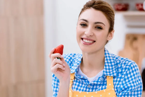 Atractiva joven en delantal con fresa - foto de stock