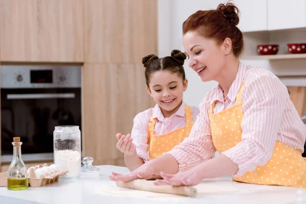 Großmutter mit kleiner Enkelin rollt Teig für Plätzchen — Stockfoto