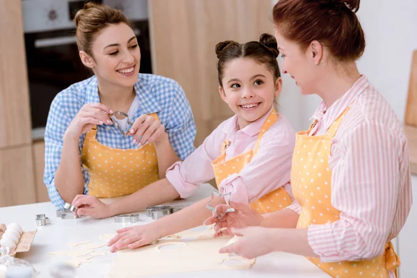 Tres generaciones de hermosas mujeres cocinando juntas en la cocina - foto de stock