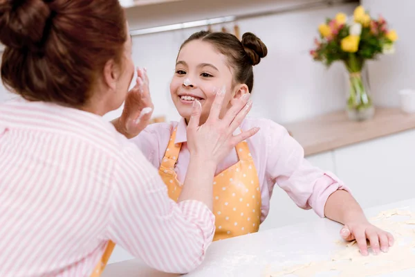 Nonna e nipotina che giocano con la farina in cucina mentre cucinano — Foto stock