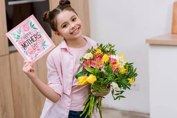Adorable little child with with bouquet and mothers day greeting card — Stock Photo