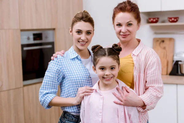 Drei Generationen von Frauen stehen zusammen in der Küche und schauen in die Kamera — Stockfoto