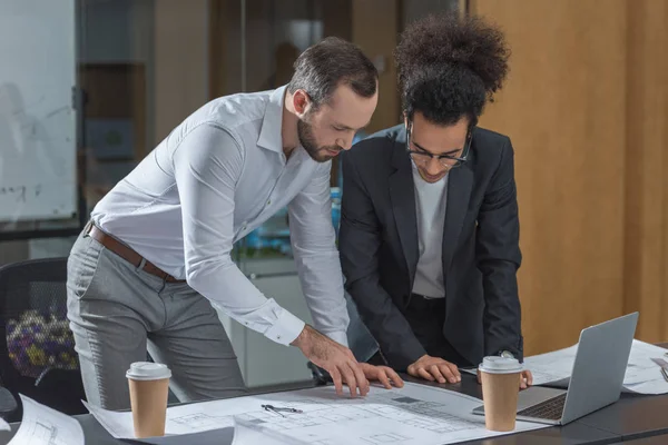 Arquitectos guapos discutiendo planes de construcción en la oficina - foto de stock