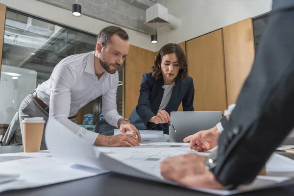 Equipo de arquitectos lluvia de ideas sobre los planos de edificios en la oficina moderna - foto de stock