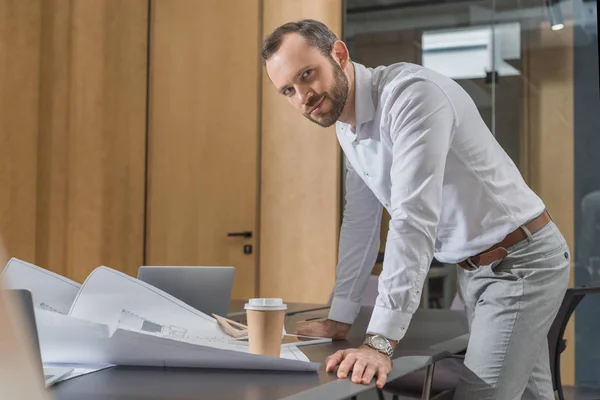 Beau architecte heureux de travailler avec des plans de construction au bureau — Photo de stock