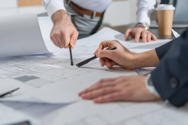 Cropped shot of architects working with building plans together at office — Stock Photo