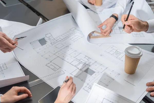 Tiro recortado de equipe de arquitetos brainstorming em planos de construção — Fotografia de Stock