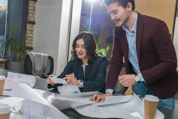 Young team of architects working with building plans together at office — Stock Photo