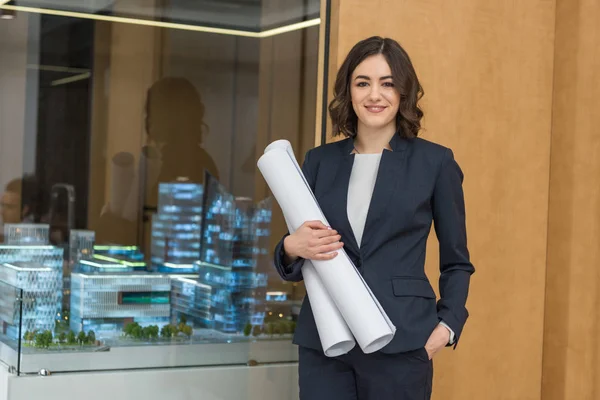 Beautiful young architect with rolled building plans — Stock Photo