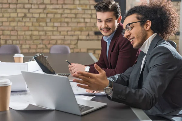 Jóvenes arquitectos exitosos trabajando juntos con el ordenador portátil en la oficina - foto de stock