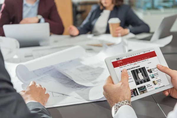 Corte tiro do arquiteto usando tablet com bbc site na tela enquanto tendo conferência — Fotografia de Stock