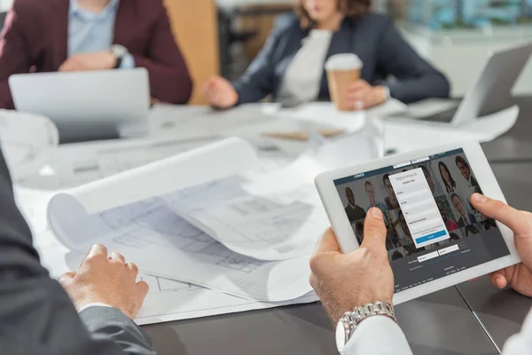 Cropped shot of architect using tablet with linkedin website on screen while having conference — Stock Photo