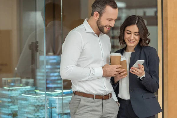 Kollegen trinken Kaffee und nutzen gemeinsam ihr Smartphone — Stockfoto