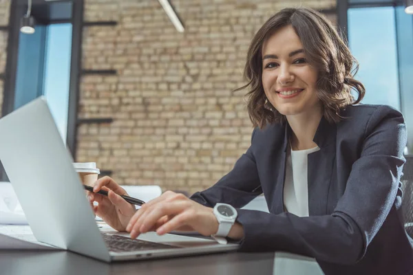 Belo jovem arquiteto trabalhando com laptop e olhando para a câmera — Fotografia de Stock