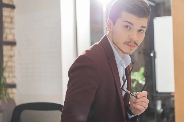 Handsome young man in suit and with eyeglasses looking at camera — Stock Photo