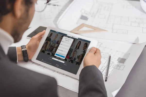 Cropped shot of young architect using tablet at workplace with linkedin website on screen — Stock Photo
