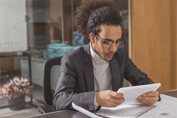 Fokussierter junger Architekt mit Tablet am Arbeitsplatz im modernen Büro — Stockfoto