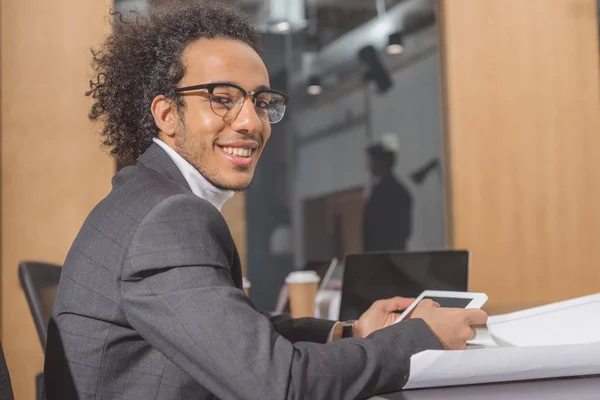 Bello giovane architetto in giacca e cravatta seduto sul posto di lavoro in ufficio e utilizzando tablet — Foto stock