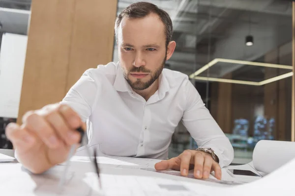 Arquitecto guapo con brújula dibujo planos de construcción en la oficina - foto de stock