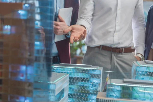Обрізаний знімок бізнесмена, що показує мініатюрну модель сучасного міста клієнтам — стокове фото