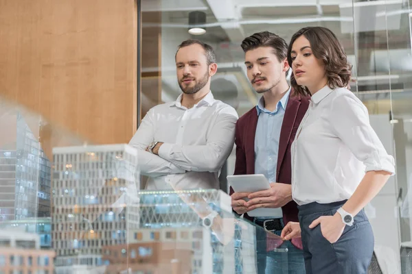 Team of serious architects looking at miniature town model — Stock Photo