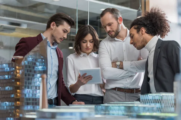 Group of architects using table together next to building models at office — Stock Photo