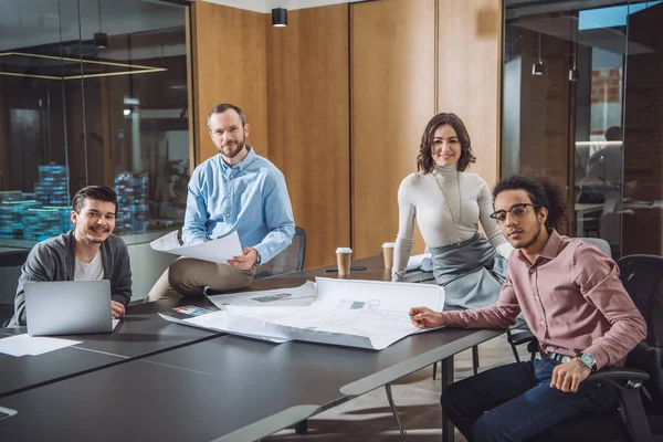 Grupo de arquitetos de sucesso sentado na sala de conferências do escritório e olhando para a câmera — Fotografia de Stock